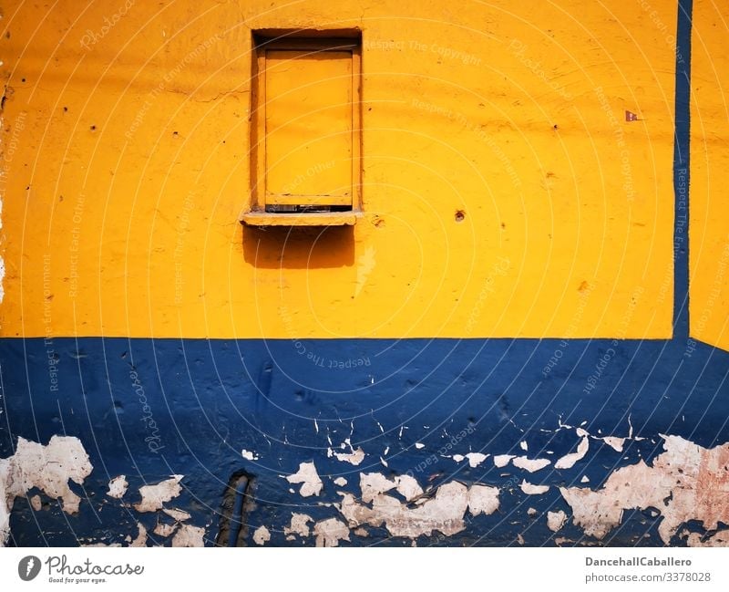 blaue gelbe Wand mit einem geschlossenem Fenster Mauer alt Fassade Architektur trist Gebäude kaputt abblättern geometrisch Design Verfall Vergangenheit