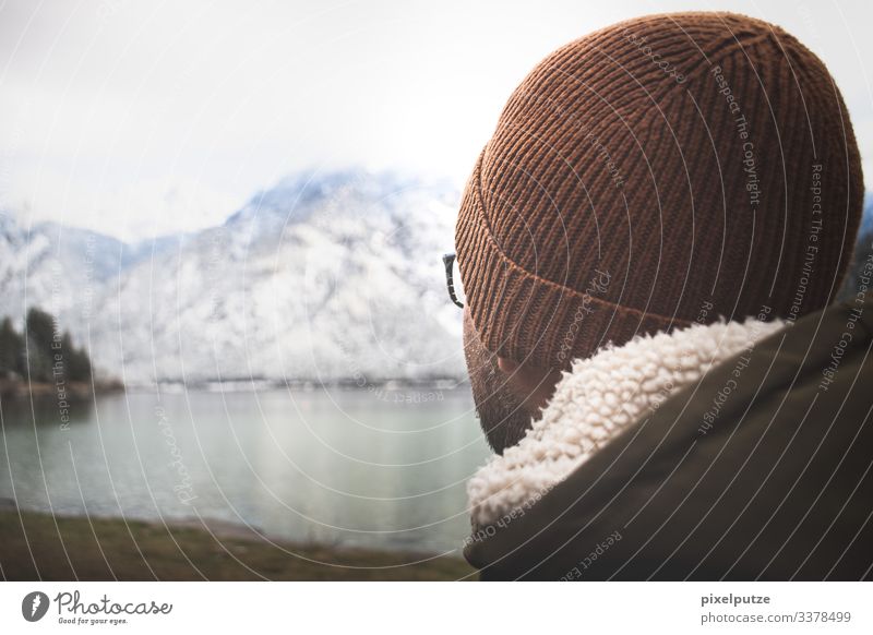 Mann mit Mütze sieht auf Bergsee Alpen Bayern Berge Brille Natur Outdoor See Weite Winter wandern