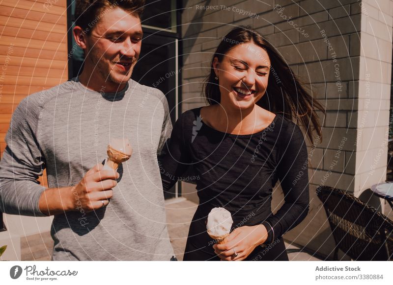 Fröhliches, entspanntes Paar lacht beim Verlassen des Cafés und beim Eisessen an einem sonnigen Sommertag Speiseeis heiter Lachen Straße Partnerschaft