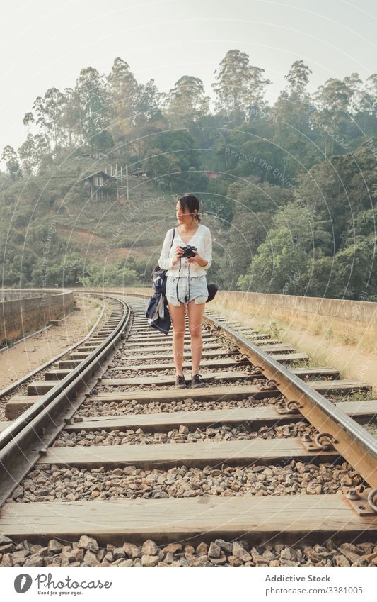 Touristin wandert auf einsamer Eisenbahn gegen exotischen Wald Frau fotografieren Fotokamera Spaziergang leer Fotografie grün Brücke Pflanze Tourismus reisen