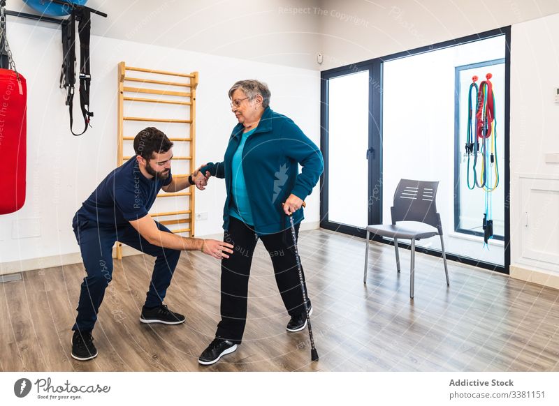 Männlicher Ausbilder unterstützt alte Frau beim Trainieren im Fitnessstudio Trainerin Physiotherapie Senior Wiederherstellung Übung Personal männlich gealtert