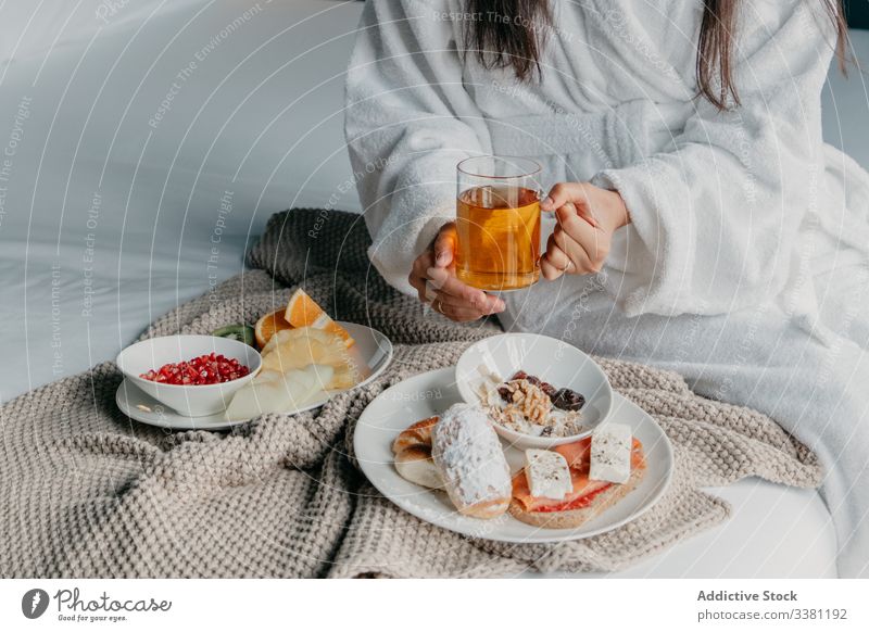 Anonyme Frau beim Frühstück im Bett Tee Glück Bademantel heiter Becher Tasse trinken Lebensmittel gemütlich geschmackvoll heimwärts sich[Akk] entspannen frisch