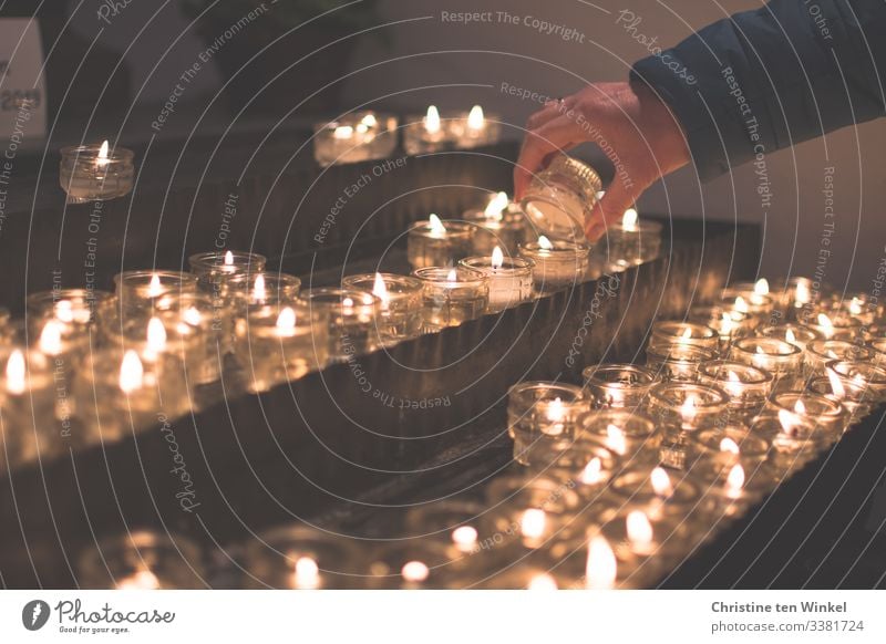 Frau zündet eine Kerze an einem Kerzenaltar an Mensch feminin Erwachsene Hand 1 30-45 Jahre 45-60 Jahre Kerzenschein Kerzenstimmung Kerzenglas Kerzenflamme