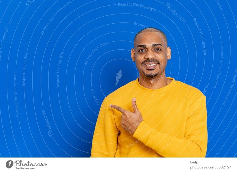 Afrikaner mit gelbem Trikot schwarz Typ blau Punkt zeigen hindeutend Finger Inserat Anzeige Erwachsener Menschen Person Afrikanisch männlich Amerikaner Mann