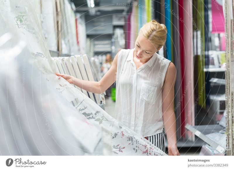 Schöne Hausfrau kauft weiße Vorhänge im Einrichtungshaus. Werkstatt Frau Laden kaufen Textilien schön Einzelhandel Käufer Wahl Sale wählen Design Mädchen