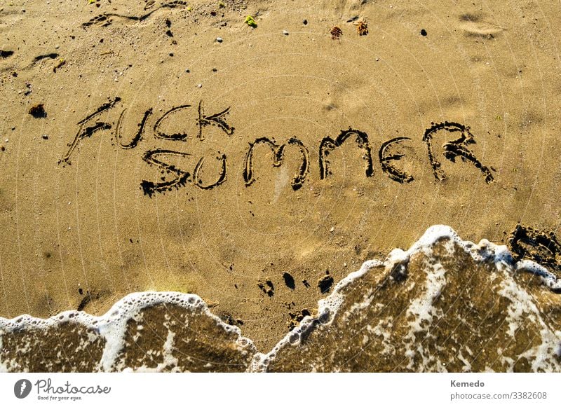Phrase "Scheiß auf den Sommer" auf den Strandsand schreiben, während an einem sonnigen Tag eine Welle ankommt. Konzept des Hasses oder der Ablehnung des Sommers mit Kopierraum.