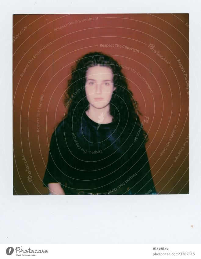 Analoges Polaroid- Portrait einer jungen Frau vor roter Wand Blick in die Kamera Porträt Zentralperspektive Schwache Tiefenschärfe Kunstlicht Tag
