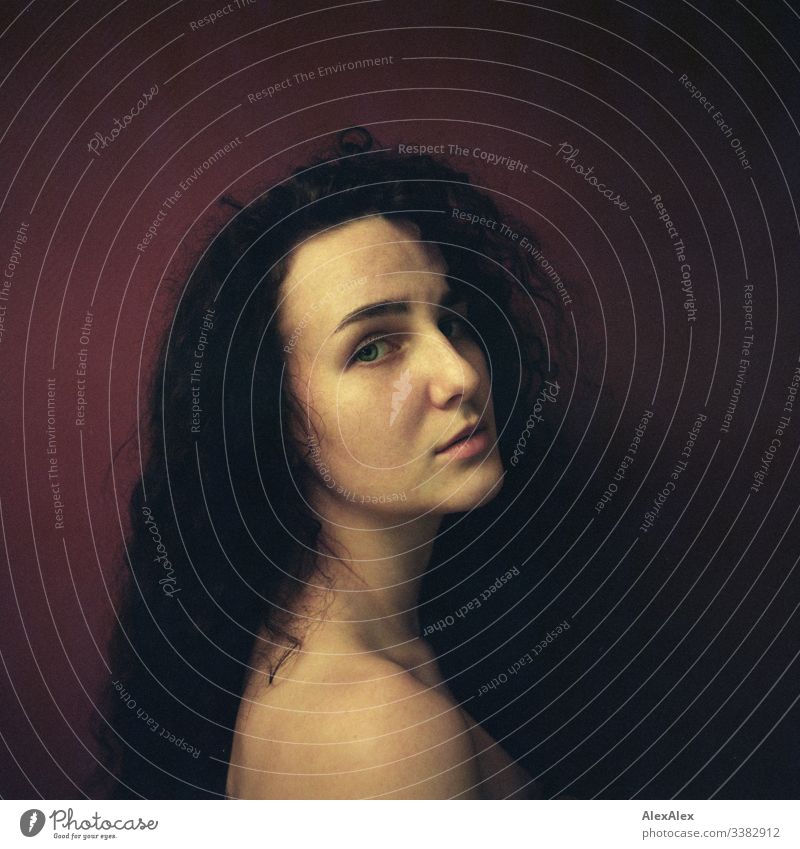 Analoges Portrait einer jungen Frau vor roter Wand Blick in die Kamera Porträt Zentralperspektive Schwache Tiefenschärfe Kunstlicht Tag Textfreiraum rechts