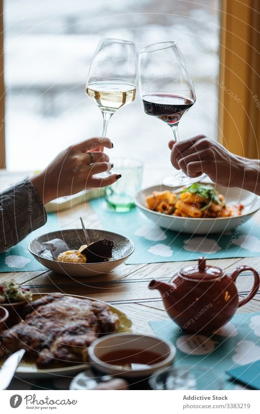Gesichtsloses Paar, das im Restaurant gemeinsam mit Wein anstößt Glas Röstung Hand Abendessen Tisch feiern männlich Frau modern Getränk trinken Alkohol