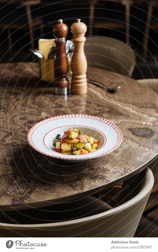 Gemüsesalat in weißer Platte auf Marmortisch im Restaurant Salatbeilage Tomate Blumenkohl grün Veganer kulinarisch Kraut Lebensmittel geschmackvoll lecker