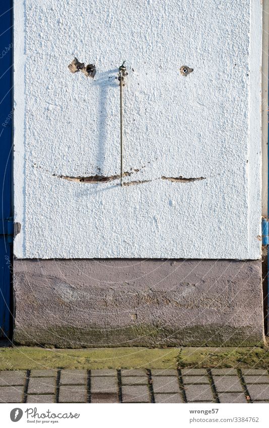 Ein stählerner Haken hängt zwischen 2 Toren herunter Befestigung Sicherung Kratzer Riefen Gebrauchsspuren Putz Putzfassade Garagenwand Schattenspiel Wand