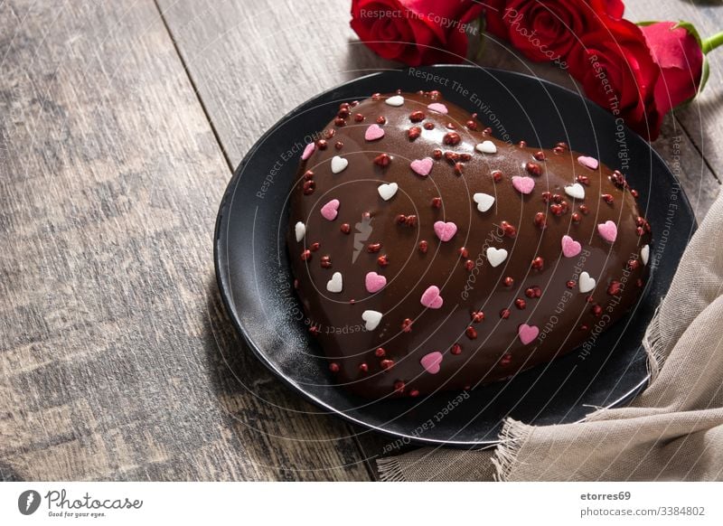Herzförmiger Kuchen und rote Rosen auf Holztisch gebacken Bäckerei schwarz Schokolade gekocht ausschneiden lecker Dessert Geschmack Lebensmittel Feiertag