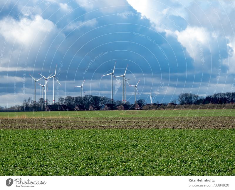 Windräder nahe Wohnhäusern und Feldern Windpark Repowering Farbfoto Landschaft Erneuerbare Energie Wetter Wolken Regenwolken Außenaufnahme Natur Umwelt