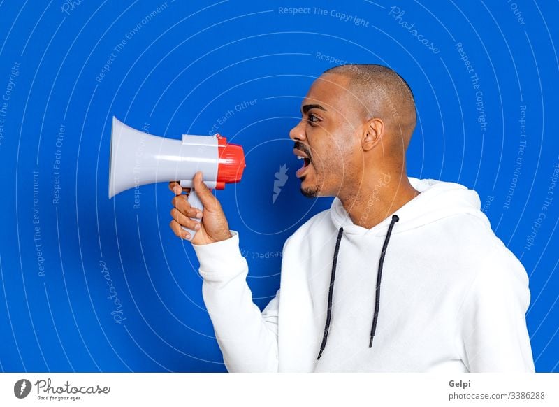 Afrikanischer Typ mit weißem Sweatshirt schwarz blau Megaphon Lautsprecher laut Redner Schreien ankündigen Stimme schreiend Kommunizieren Ankündigung Anzeige