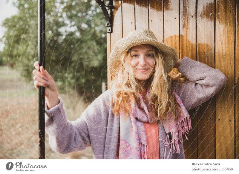 Junge Frau mit Strohhut reist mit einem Retro-Holzzug. Sonnenuntergangslandschaft, Wind in blonden Haaren. Mädchen lächelt fröhlich. Mallorca, Spanien.