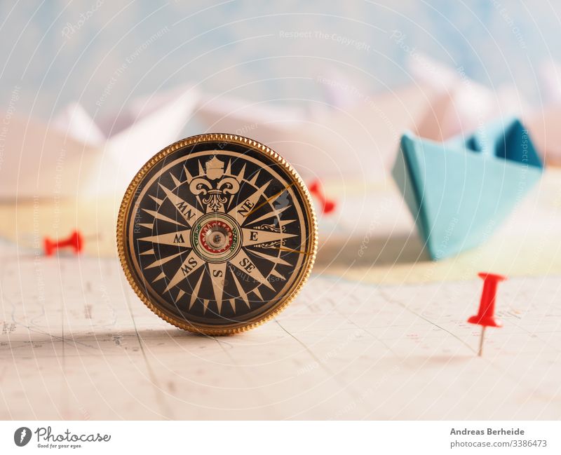 Nahaufnahme eines Kompasses und Standortmarkierung mit einer roten Nadel auf der Seekarte. abstrakt Abenteuer antik Antiquität Antike Hintergrund verbrannt
