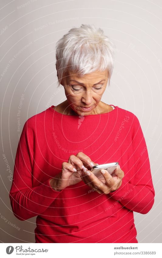 verwirrte ältere Frau, die ein Smartphone benutzt reif Senior Dame Mobile Zelle Telefon Oldtimer Erwachsener Verwirrung Oma Großmutter betrachtend modern