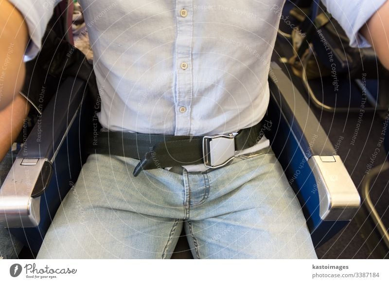 Männlicher Passagier mit angeschnalltem Sicherheitsgurt, während er im Flugzeug sitzt, um einen sicheren Flug zu gewährleisten. Ebene befestigt befestigen Gurt