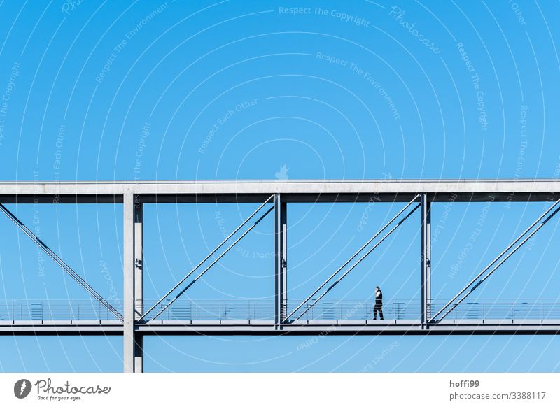 Mann geht über eine minimalistische Brücke mit tiefblauem Himmel Wegsehen Hintergrund neutral Berlin ästhetisch Betonbauweise Deutscher Bundestag abwärts