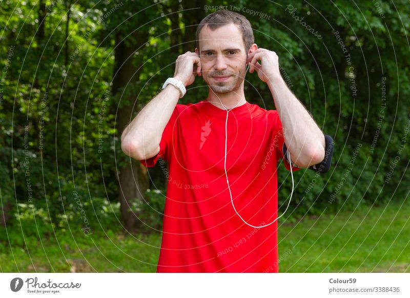 Junger Sportler mit Kopfhörern jung Musik Mann gutaussehend hören Training Übung Fitness Lifestyle Typ Gesundheit Telefon Athlet Erwachsener Aktivität im Freien