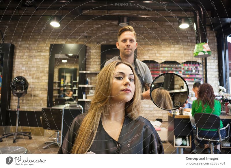 Kaukasische Frau lässt sich in einem hippen Friseursalon die Haare frisieren Themen der Friseurin verwöhnende Glamour-Haarpflege Haarschnitt Salon Hipster