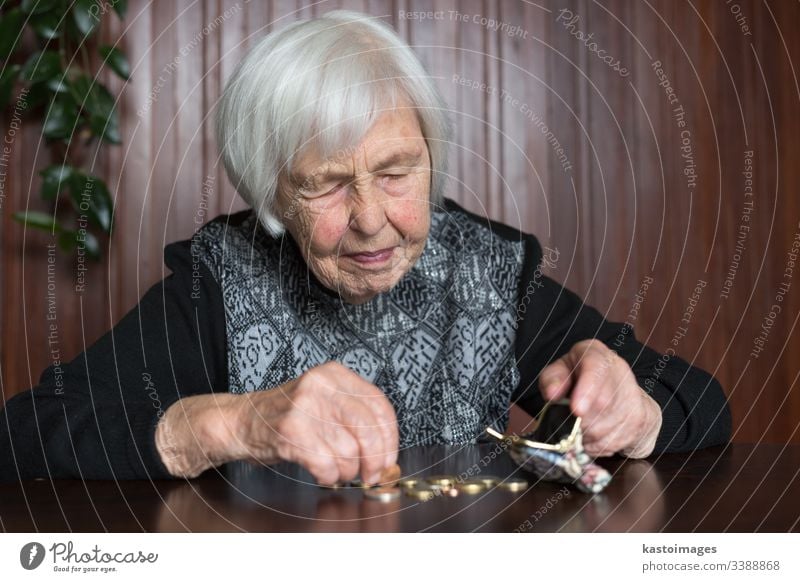 Ältere Frau, die am Tisch sitzt und Geld in ihrer Brieftasche zählt. Senior Rentnerin älter Armut Ruhestand alt leer Münzen Hintergrund unglücklich pleite