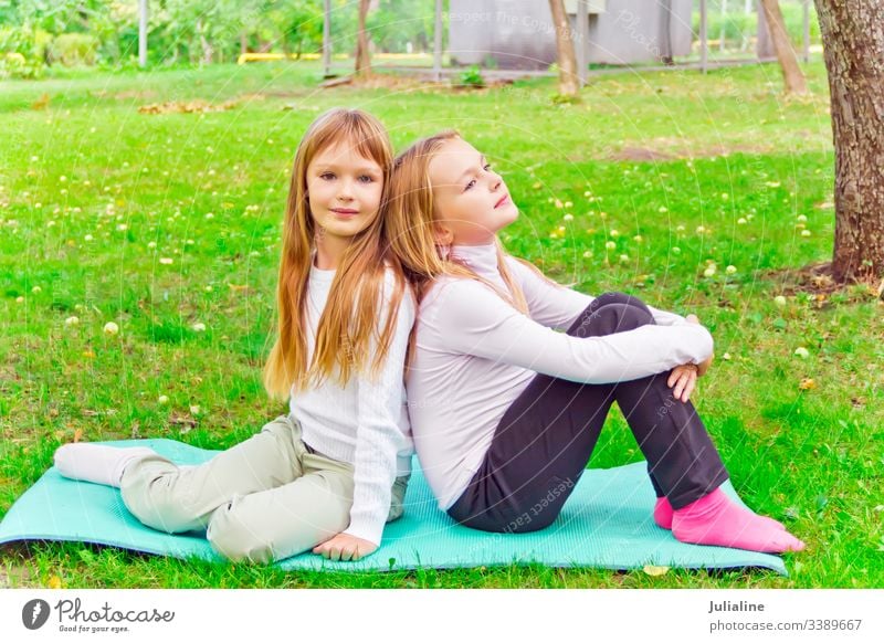 Zwei siebenjährige Mädchen sitzen auf grünem Gras Schwester spielen zwei Frau Lebensstile Freizeit Aktivität entspannend Kind Lächeln Vorschulkind Schulmädchen