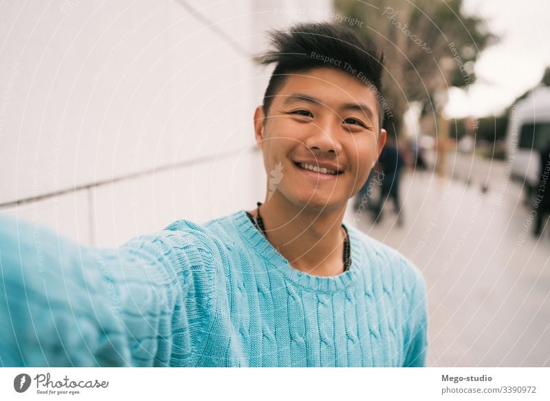 Ein asiatischer Mann, der sich einen Selfie nimmt. selbstbewusst Blick Typ Selbst Hintergrund Lächeln Männer Gesicht urban Stadtleben Profil heiter Bild
