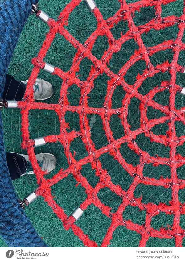Schaukel mit rotem Seilnetz pendeln Netz Spielplatz Boden abstrakt Kindheit spielerisch lustig Turnschuh Fuß