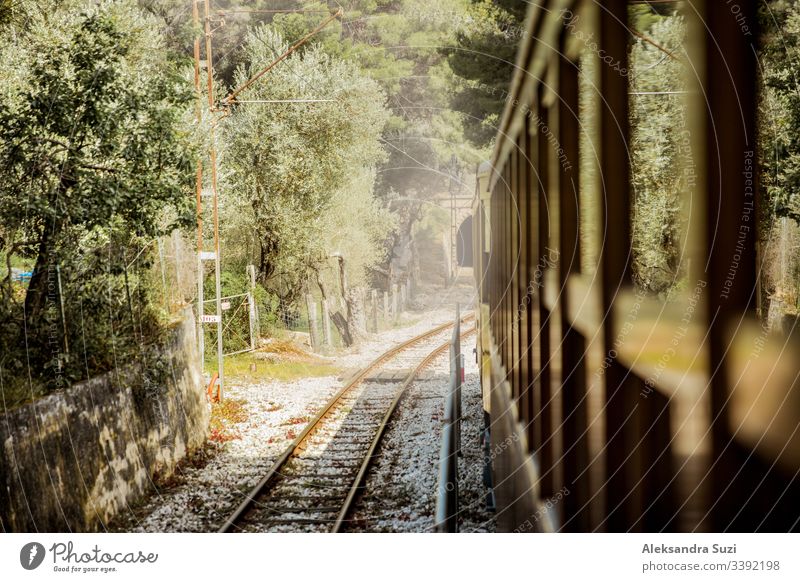 Retro-Holzzug, der entlang einer Eisenbahn in den Bergen fährt. Wunderschöne sonnige Sommerlandschaft. Mallorca, Spanien. Abenteuer Pendler Landschaft