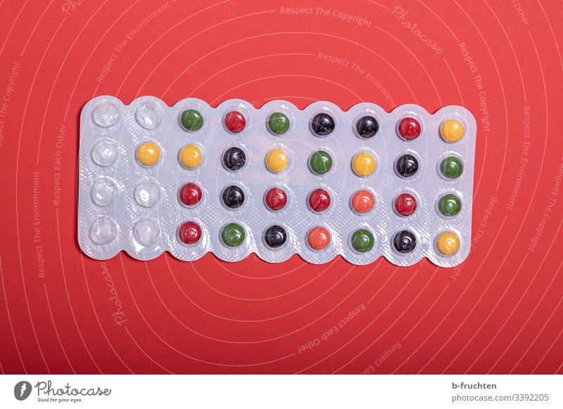 Bunte Pillen auf rotem Hintergrund pillen Medizin Arznei Nahaufnahme Gesundheit Behandlung Süssigkeit Kaugummi Droge bunt Dragees Tabletten Pharmazie