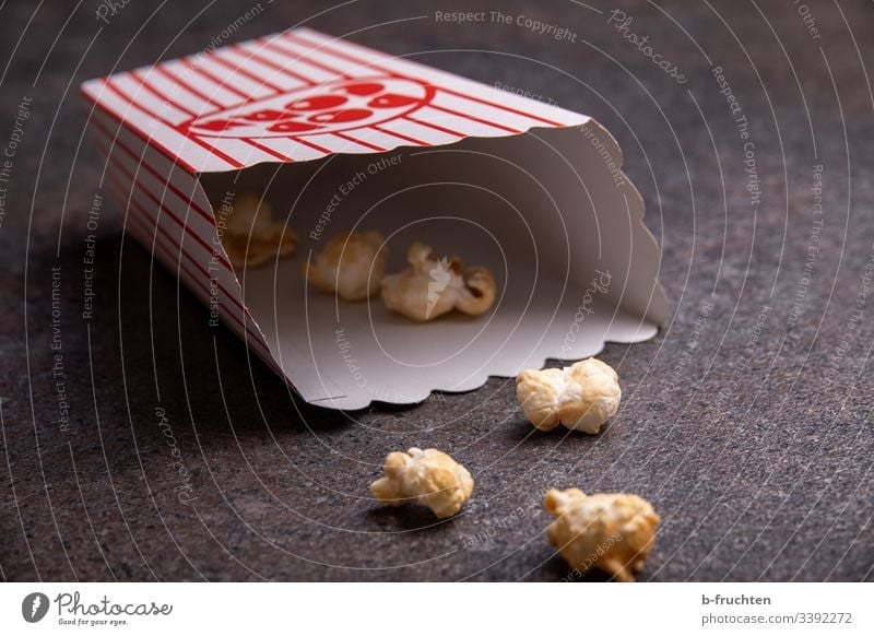 Ein paar Popcorns in einer Tüte am Boden Popkorn Kino Rest Innenaufnahme Lebensmittel Snack lecker Mais Nahaufnahme Fastfood Essen salzig süß Süßwaren ungesund