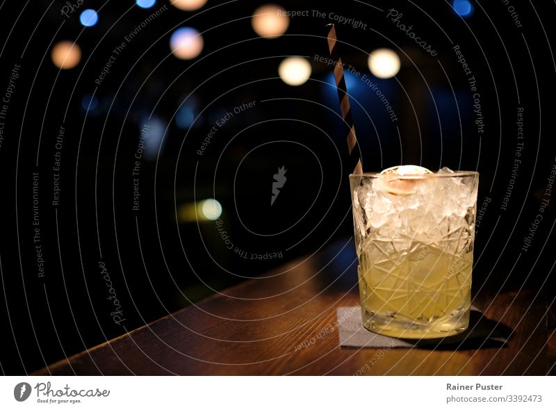 Erfrischender Cocktail in einer Bar mit Bokeh-Licht im Hintergrund Cocktailbar Glas erfrischend Nachtleben dunkel Eiswürfel cool Windstille Gelassenheit Stroh