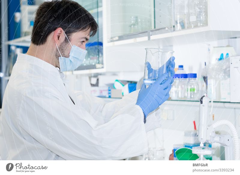Mann im Labor, der ein Glas hält und die Flüssigkeit darin beobachtet Analyse Analysieren biologisch Biotechnologie Pflege Chemikalie Chemiker Chemie Klinik