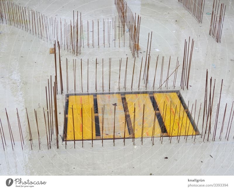 Betonfundament mit senkrechten Moniereisen und Holzabdeckung über Bodenöffnung Baustelle Fundament Außenaufnahme Menschenleer bauen Farbfoto Arbeitsplatz