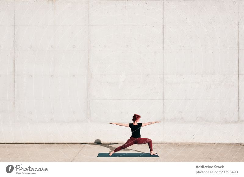 Frau macht Krieger-Zwei-Yoga-Pose auf der Straße Dehnung üben Asana Training Übung beweglich Athlet Windstille gymnastisch Beton urban Wellness Wohlbefinden