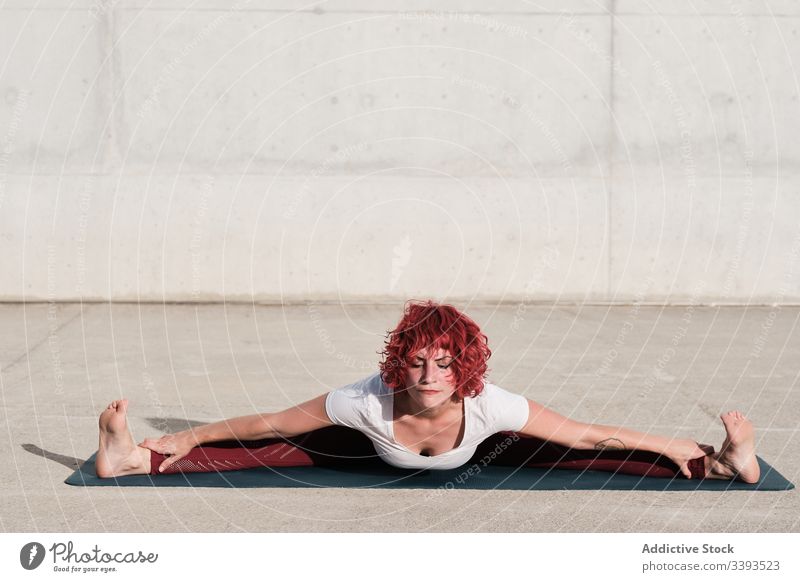 Flexible junge Sportlerin praktiziert Yoga im Gleichgewicht auf der Strasse Straße beweglich Übung Dehnung Frau akrobatisch üben Training gymnastisch Schatten