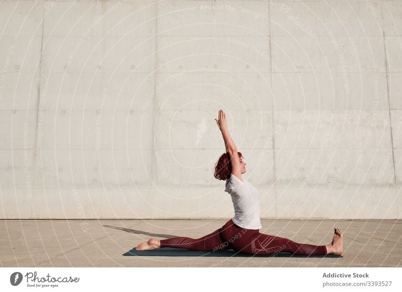 Flexible junge Sportlerin, die auf der Straße Yoga praktiziert beweglich Übung Dehnung Frau akrobatisch üben Training gymnastisch Schatten physisch urban