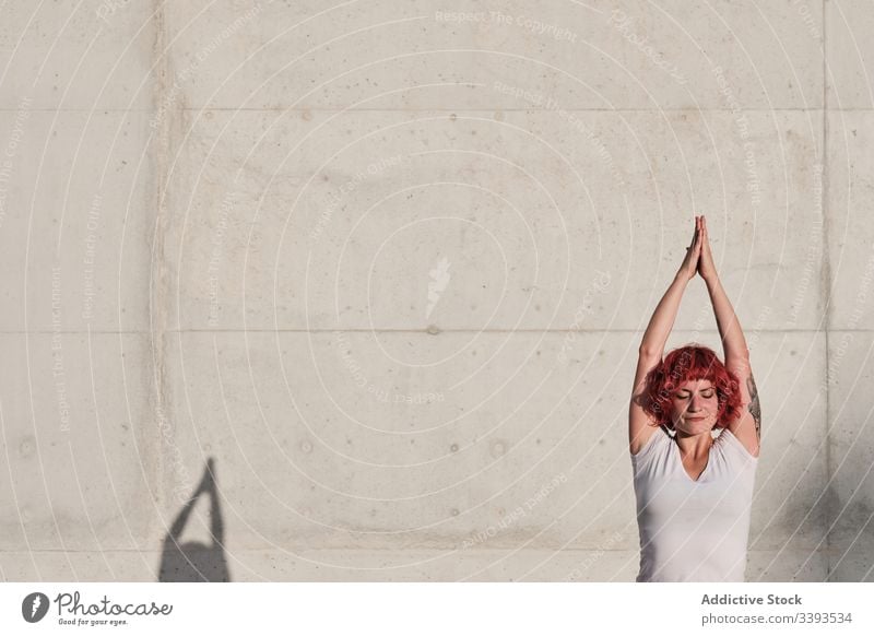 Frau in Baumpose praktiziert Yoga auf der Straße Athlet Baumhaltung Gleichgewicht Namaste meditieren üben Training Übung Dehnung Beton Windstille vrikshasana