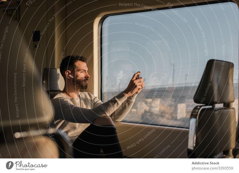 Fokussierter junger Mann fotografiert mit Smartphone in der U-Bahn fotografieren Passagier Fotografie Funktelefon Fenster Zug männlich Mitfahrgelegenheit