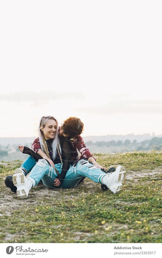 Zufriedene weibliche Teenager, die sich auf Gras umarmen Frauen Freundin Lachen Spaß Umarmung Natur Wiese bester Freund Umarmen Lächeln genießen teilen lässig