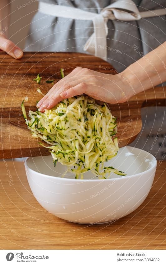 Frau legt geriebene Zucchini in Schüssel Essen zubereiten Lebensmittel Gitter Rezept Gemüse Bestandteil Küche Gesundheit Mahlzeit Hausfrau Abendessen