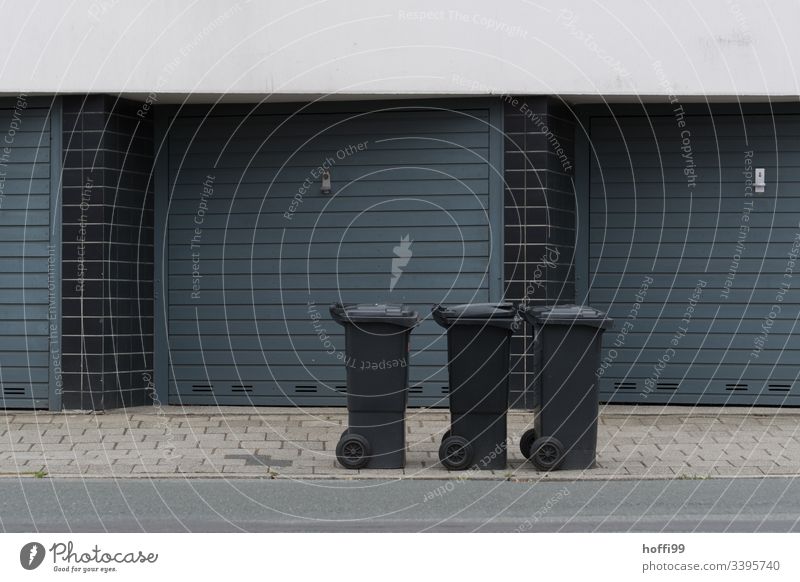 drei Mülltonnen am Strassenrand Restmüll Restmülltonne Müllabfuhr Fassade Garagentor garageneinfahrt Außenaufnahme Gebäude Einfahrt Recyclingcontainer