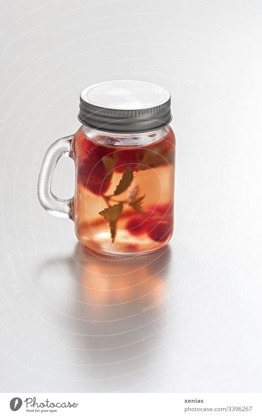Erfrischungsgetränk to go mit Erdbeeren und Zitronenmelisse im gläsernden Schraubglas Getränk To go rot kalt Glas Frucht Gesundheit kühl Hintergrund neutral