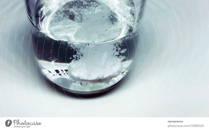 eine Brausetablette, die in einen mit Wasser gefüllten Glasbecher fällt. Seifenblasen und Sprudeln. spritzig trinken Medizin Gesundheit Schaumblase Hintergrund