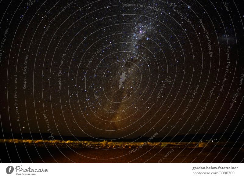Milchstrasse über Namibia Nachtaufnahme Landschaftsaufnahme wenig Farbe Sternenhimmel scharzer Himmel mit Sterne wenig Vegetation licher in der rechten Bildecke