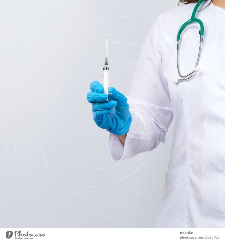 Medizinerin in weißem Mantel und blauen Latexhandschuhen, die eine Spritze hält, weißer Studiohintergrund Erwachsener Pflege Kaukasier Klinik Kur Arzt Dosis