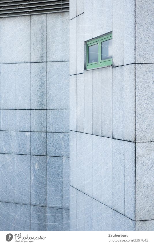 Graue Fassade aus Granitplatten mit grünem Fenster und einer Variation mit Lamellen Haus grau Platten Fugen Muster Rechteck trist trostlos menschenleer