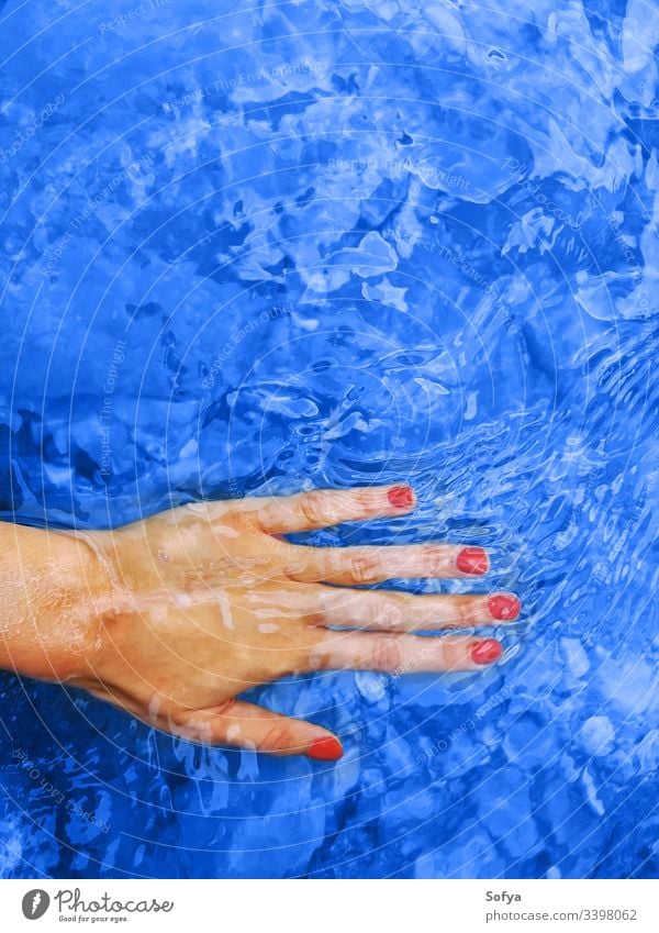 Klassische blaue Farbe des Jahres 2020. Weibliche Hand im Wasser klassisch Frau Spa Harmonie rot Maniküre Wellness Nägel Nagellack Urlaub Hintergrund