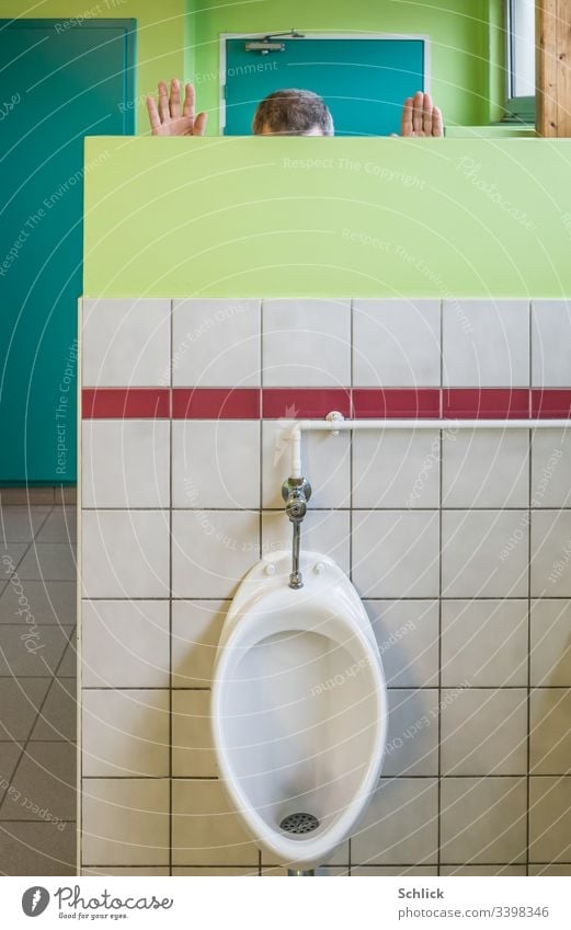 Mann pinkelt freihändig hinter Sichtschutzwand in Urinal pinkeln urinieren Witz Gags Haare Hände Kopf Schopf Kacheln WC versteckt weiß rot grün türkis Mensch